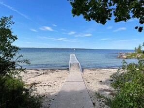 Un pilier de béton s’avançant dans une étendue d’eau calme, entouré de verdure et surplombé d’un ciel dégagé.