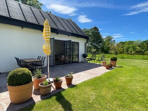 Une terrasse avec une table et des chaises, un barbecue et des plantes en pot.