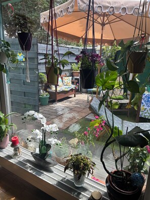 Un patio con plantas en macetas, una silla colgante y una mesa de madera.