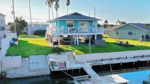 Una casa de dos pisos con balcón, piscina y muelle.