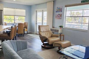 A spacious living area with a dining table, multiple chairs, a recliner, and a large window with a view. - Waterfront Three Bedroom Retreat with Hot Tub and Private Dock (Hernando Beach)