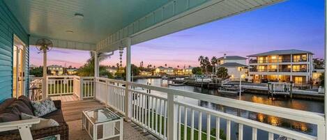 A covered outdoor deck with a view of a marina and buildings.