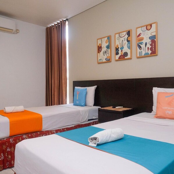 A hotel room with two beds, a nightstand, and three wall art pieces. - Prime Cailendra Hotel Tamansiswa Yogyakarta (Yogyakarta)