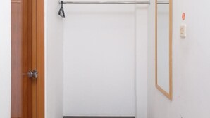 A bathroom with a wooden door, a towel rack, a mirror, and a black bench. - Prime Cailendra Hotel Tamansiswa Yogyakarta (Yogyakarta)