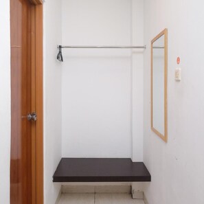 A bathroom with a wooden door, a towel rack, a mirror, and a black bench. - Prime Cailendra Hotel Tamansiswa Yogyakarta (Yogyakarta)