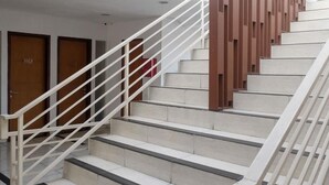 A staircase with white railings and beige steps, leading to a door with a red object on it. - Prime Cailendra Hotel Tamansiswa Yogyakarta (Yogyakarta)