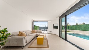 Ein modernes Wohnzimmer mit einer großen Couch, einem Couchtisch und Blick auf einen Swimmingpool.