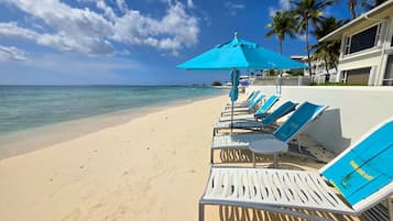 PĂ„ stranden, vit sandstrand, solstolar och parasoller