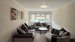Una sala de estar moderna con un sofá modular, una mesa de centro redonda y un ventanal con vistas.
