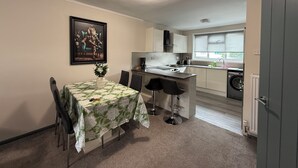 Cocina compacta con comedor, un cuadro en la pared y vista al exterior.