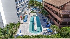 Ein Hotel mit einem zentralen Schwimmbad, mehreren Balkonen und Meerblick.
