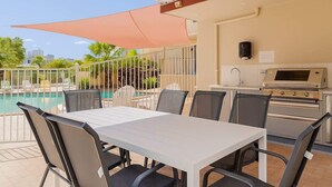 Un patio con piscina, mobiliario exterior y zona de barbacoa.
