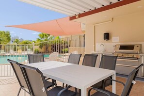 Eine Terrasse mit Pool, Sitzgelegenheiten im Freien und Grillplatz.