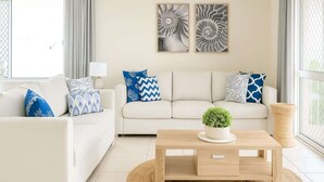 Una sala de estar con sofá, mesa de centro y cojines decorativos.