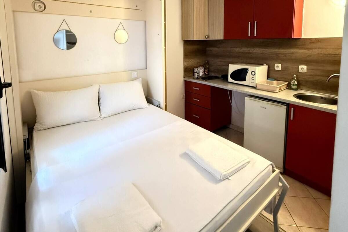 Una habitación de hotel con cama, una kitchenette pequeña y un espejo en la pared.