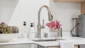 Eine moderne Küche mit einem Edelstahl-Wasserhahn, einer Schüssel Artischocken und zwei Seifenflaschen.