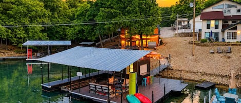 A waterfront property with a dock, outdoor seating, and a building with a covered patio.