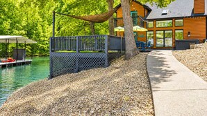 A lakeside cabin with a deck, outdoor seating, and a boat dock.