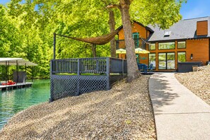 Eine Blockhütte am Seeufer mit Terrasse, Sitzgelegenheiten im Freien und einer Bootsanlegestelle.