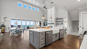Une cuisine spacieuse dotée d’un grand îlot central, d’un plancher en bois et offrant une vue sur l’extérieur.