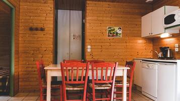 Un interior de madera con una mesa de comedor, sillas, una zona de cocina y una puerta.