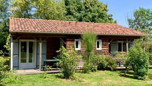 A wooden house with a tiled roof, a covered porch, and a small garden area. - Accessible Family Cottage for 6 (Moncoutant-sur-Sèvre)
