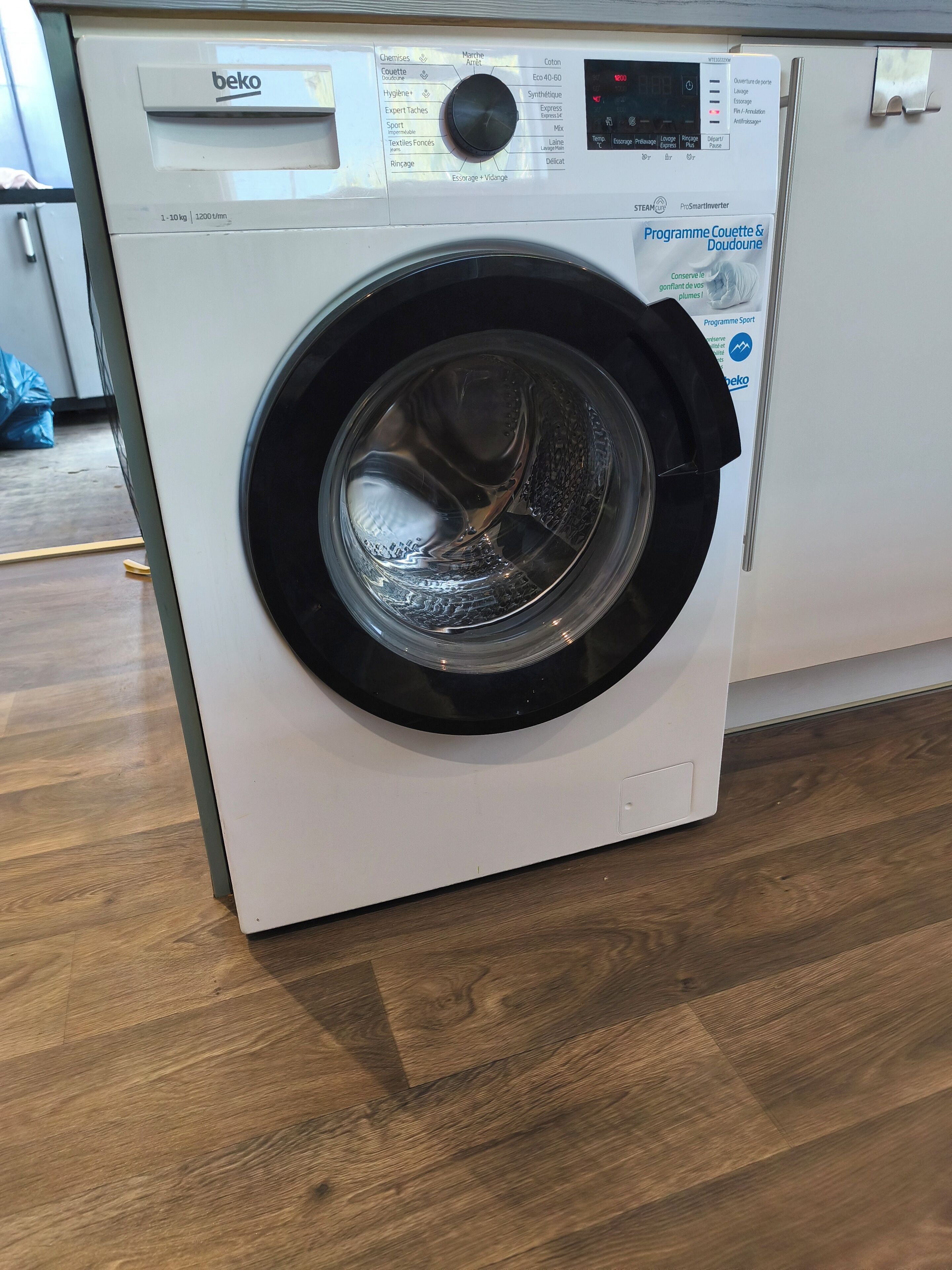 A front view of a white front-loading washing machine with a digital display and multiple control buttons.