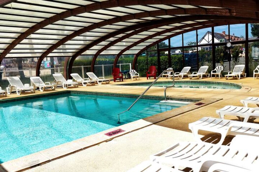 Una piscina interior con sillones de descanso y una zona cubierta.