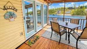 A deck with a table and chairs, a welcome sign, and a view of a lake. - Lakeside Escape with Boat Slip (Rocky Mount)