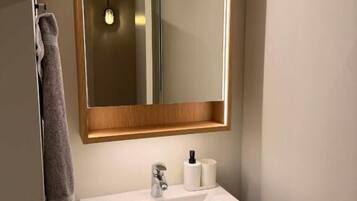 A bathroom with a white sink, a mirror, and a towel hanging on the wall.