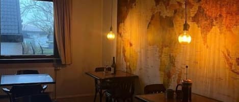 Un interior de restaurante con mesas y sillas, un mapa grande en la pared y lámparas colgantes.