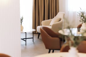 Una sala moderna con un sillón color beige, una mesa de centro redonda y una planta en maceta.