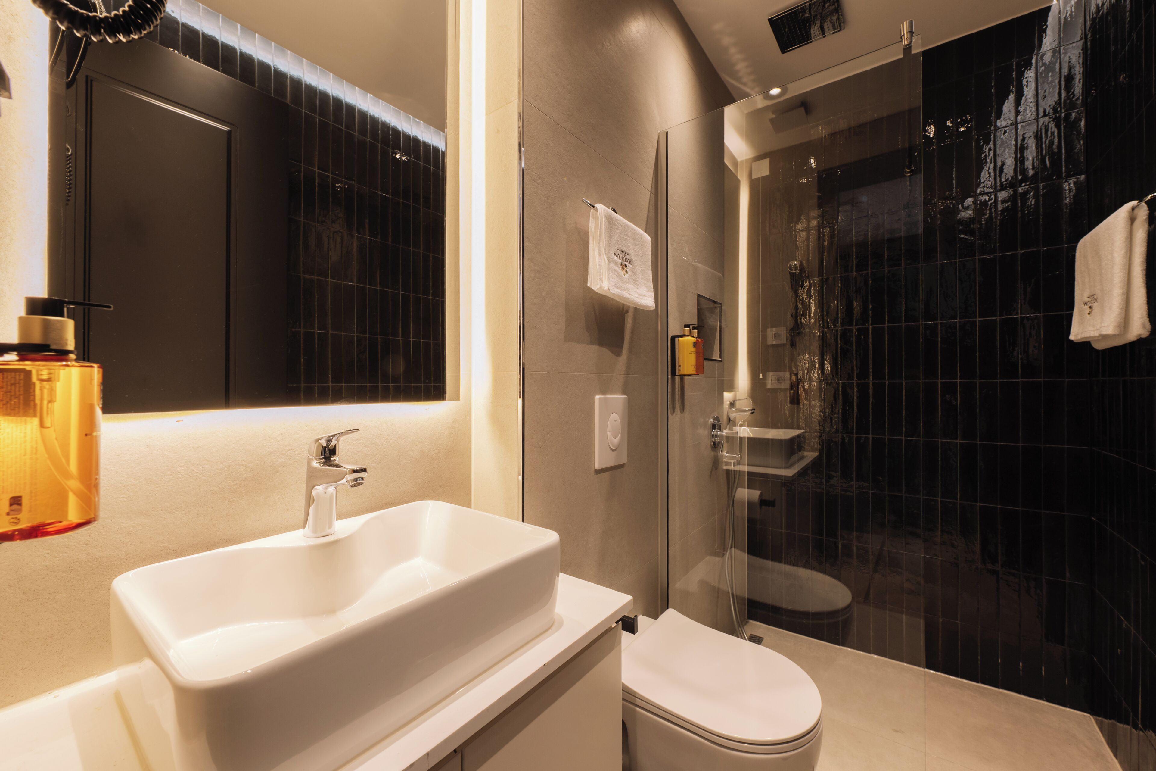 A modern bathroom with a white sink, a toilet, and a glass-enclosed shower area.