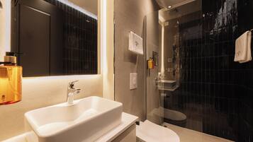 A modern bathroom with a white sink, a toilet, and a glass-enclosed shower area.