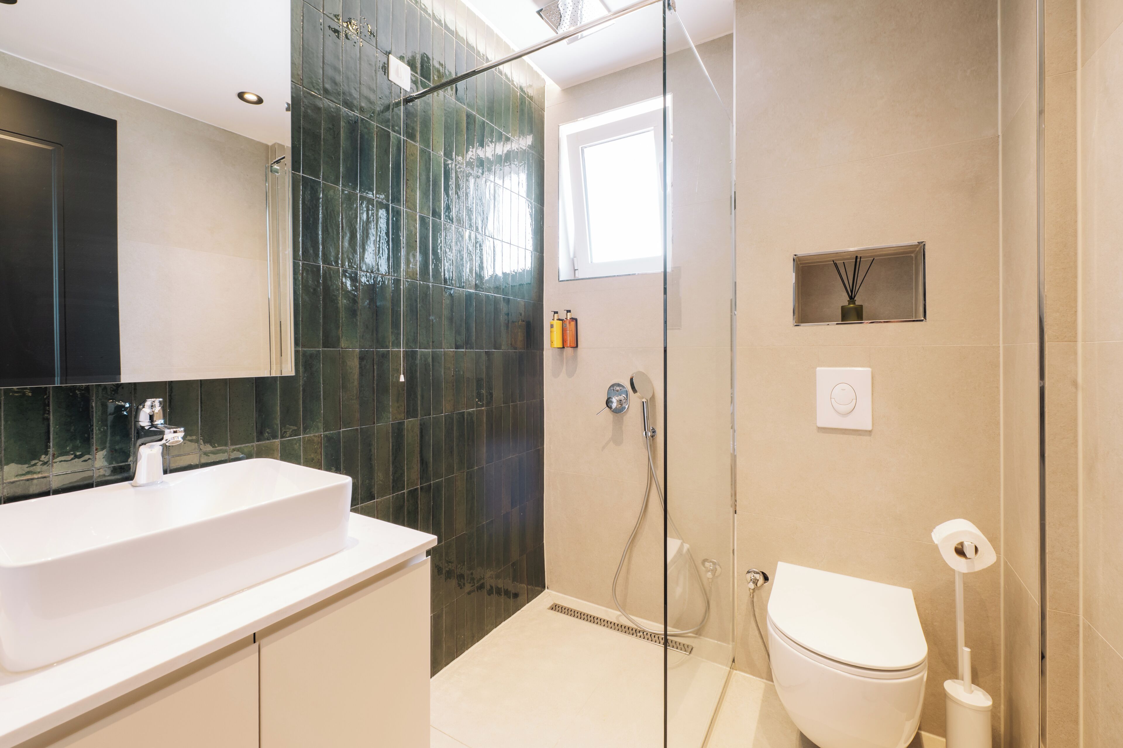 Een moderne badkamer met een glazen douchecabine, een wit wastafelmeubel en een toilet.