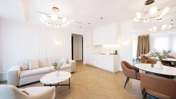 A modern living room with a sofa, coffee table, and dining area with chairs and a table.