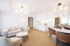 A modern living room with a sofa, coffee table, and dining area with chairs and a table. - Hotel Dolcinium (Ulcinj)