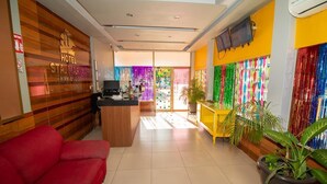 A hotel reception area with a red sofa, a wooden reception desk, and colorful decorations on the walls. - Hotel Santa María (Mazatlán)