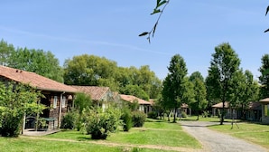 A rural setting with traditional buildings, a gravel path, and lush greenery. - Nature Cottage Near Puy du Fou (Moncoutant-sur-Sèvre)