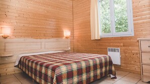 A wooden-paneled room with a bed, a window, a heater, and a dresser. - Nature Cottage Near Puy du Fou (Moncoutant-sur-Sèvre)
