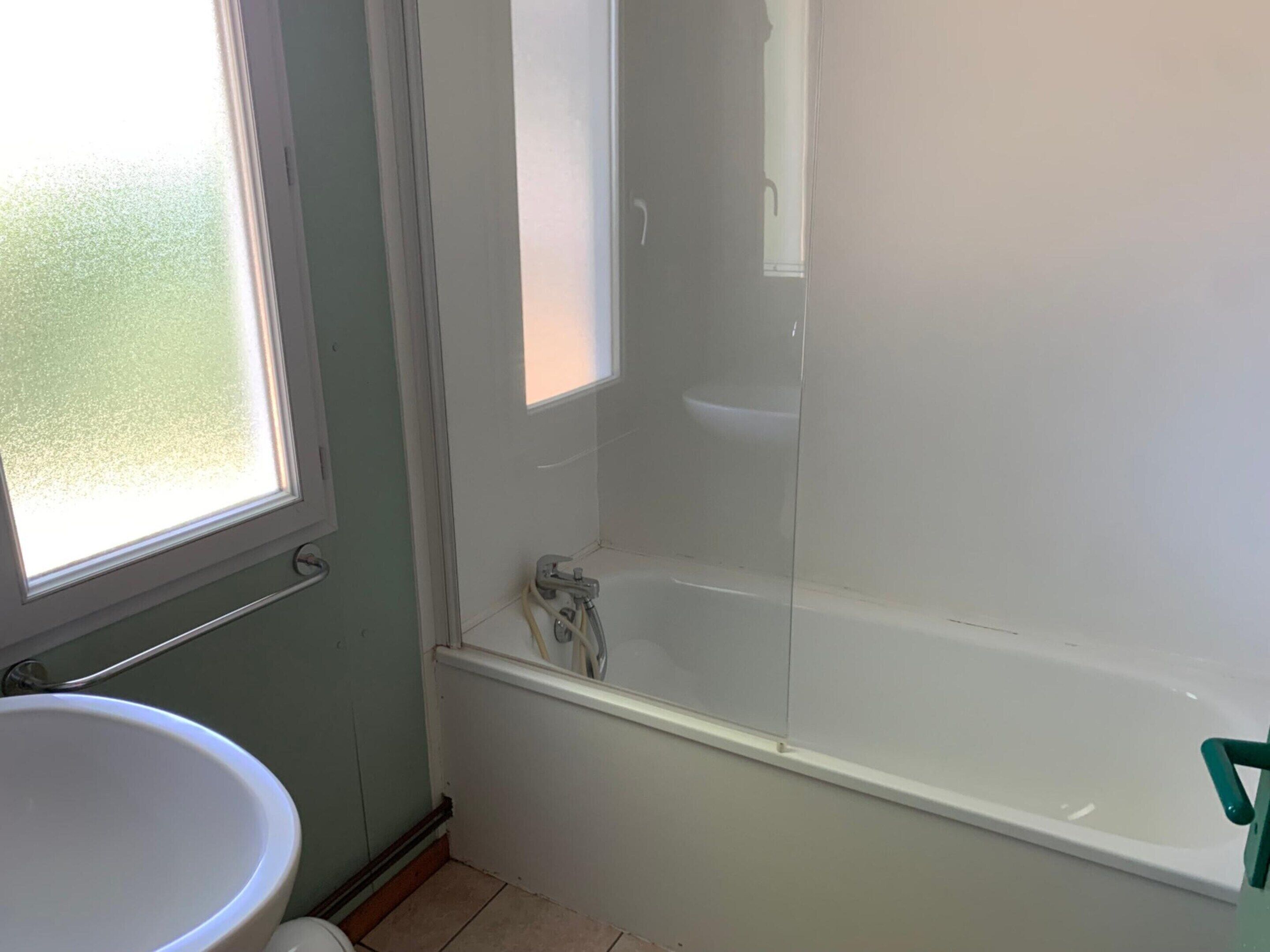 Un baño con bañera, ventana y lavabo.