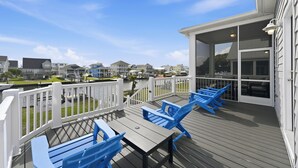 Een terras met blauwe stoelen en een tafel, met uitzicht op een waterpartij met huizen op de achtergrond.
