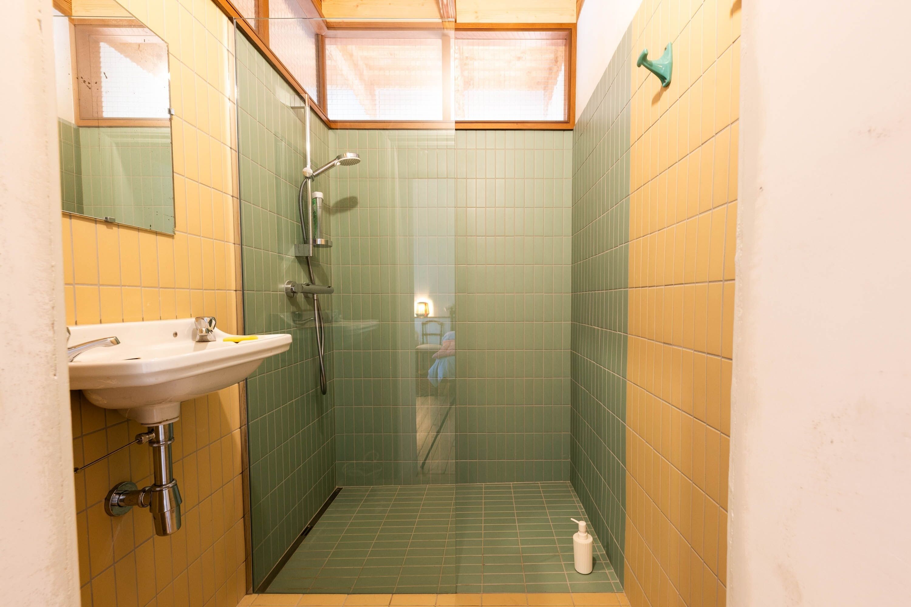 Un baño pequeño con lavamanos, espejo e inodoro con ducha.