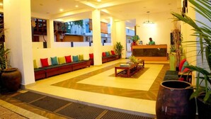 Un hall de hotel con mostrador de recepción, zona de estar y vistas al exterior.