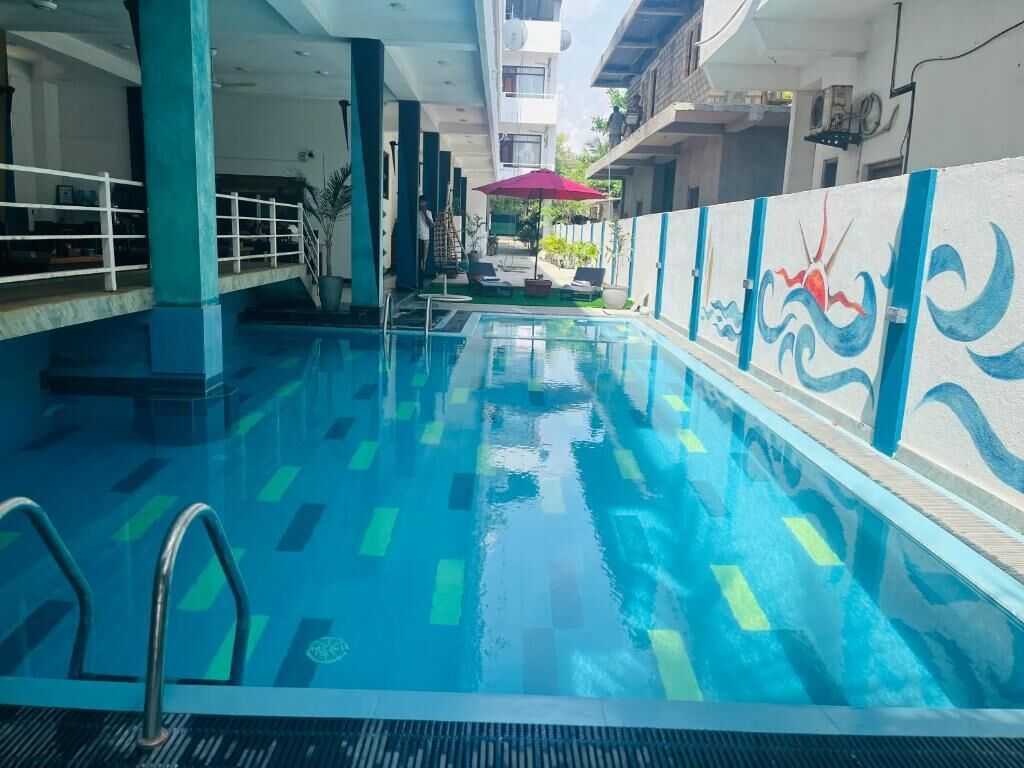 Piscina interior con agua azul cristalina, una escalera metálica y un mural en la pared.