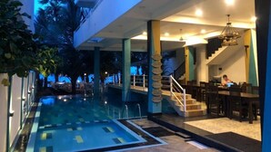 Una piscina con solárium de baldosas, una escalera y una zona de bar con asientos.