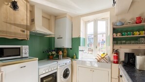 Cozinha compacta com micro-ondas, forno, máquina de lavar roupa e janela com vista.