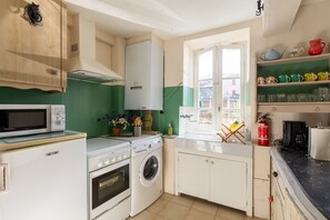 Eine kompakte Küche mit Mikrowelle, Backofen, Waschmaschine und Fenster mit Blick.