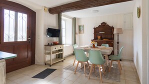 Uma área de refeições com mesa, cadeiras, televisão e um armário de madeira.