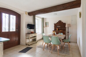 Ein Essbereich mit Tisch, Stühlen, einem Fernseher und einem Holzschrank.